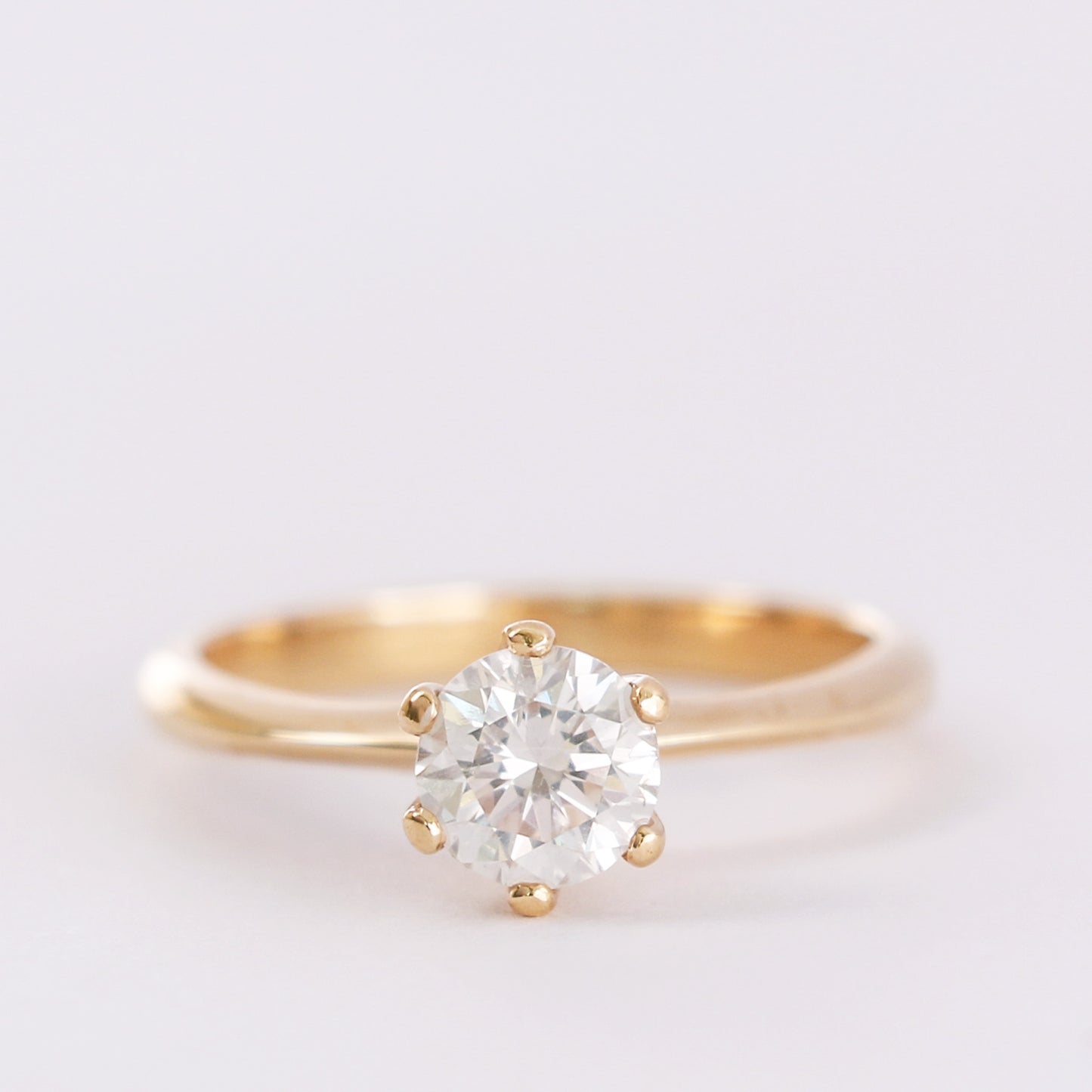 yellow gold six prong diamond ring on white gray background