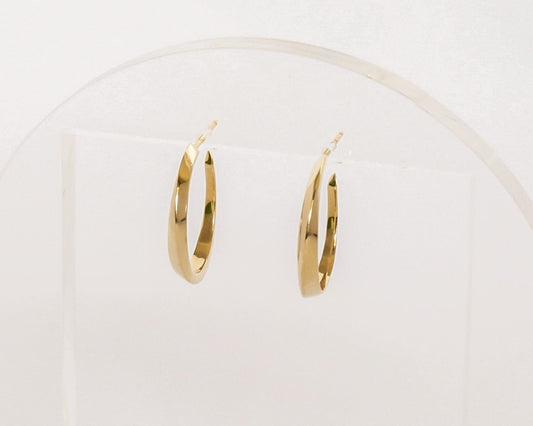 Small 14K gold twist hoop earrings with geometric sculpted design, minimalist modern jewelry displayed on clear acrylic stand with soft lighting.