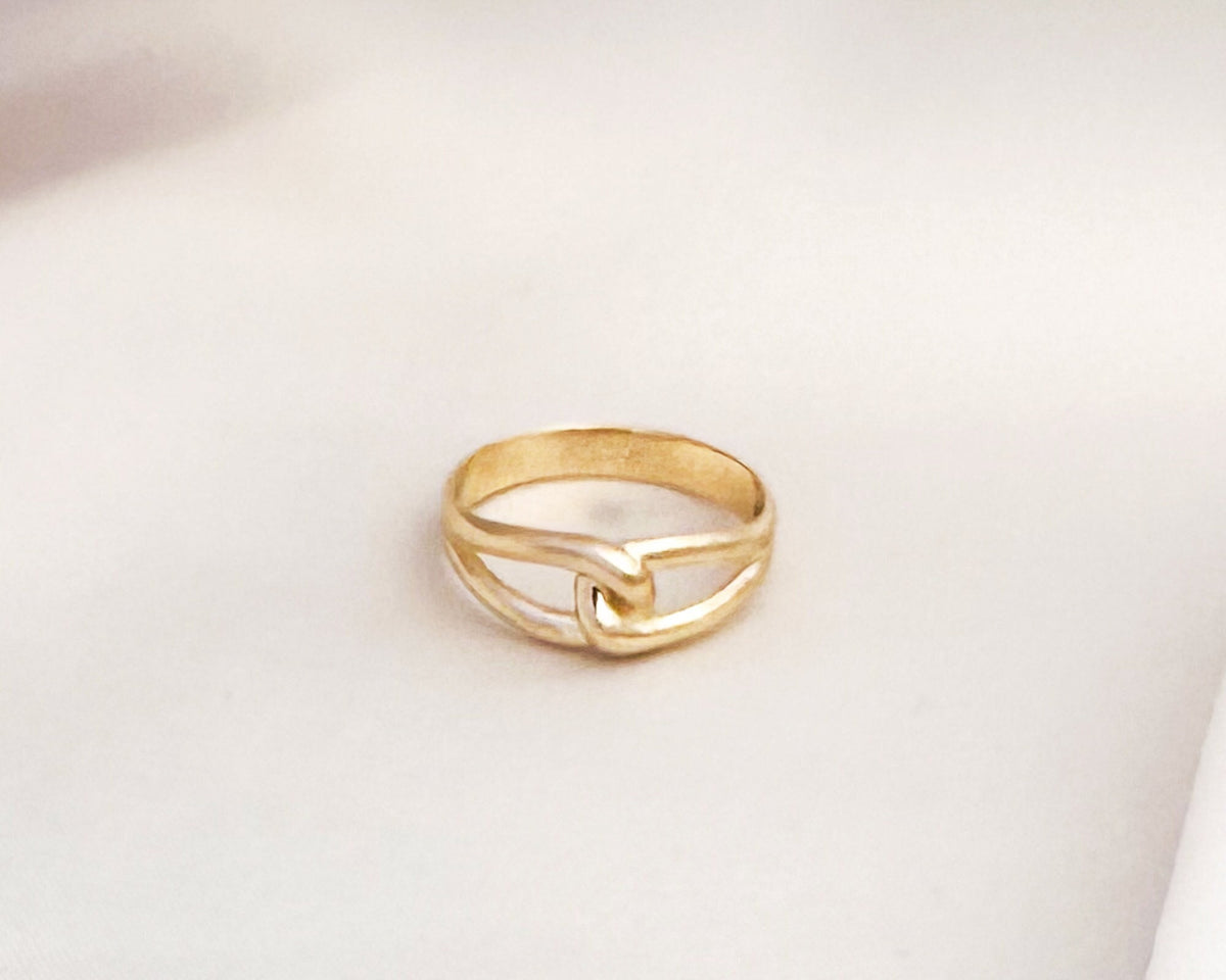 Solid yellow gold love knot ring on white fabric
