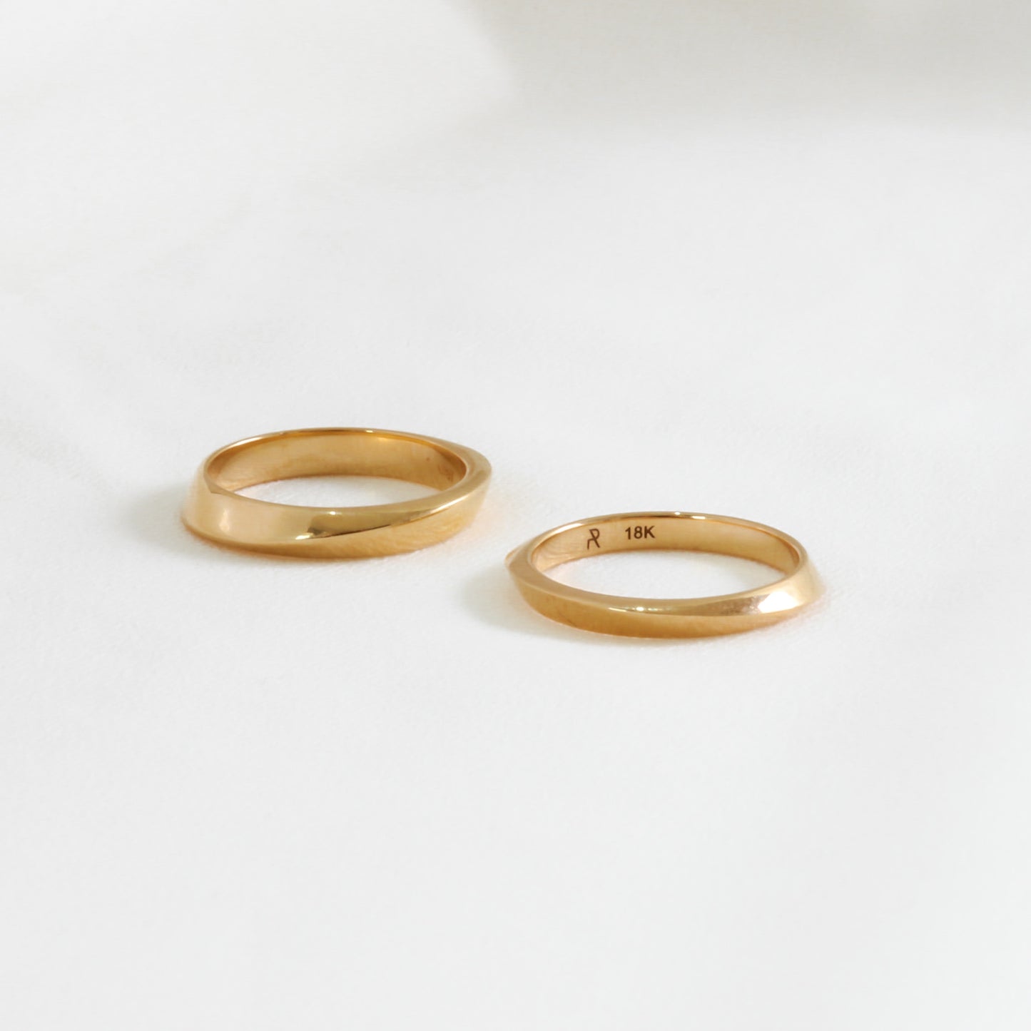 two geometric gold wedding rings on white background