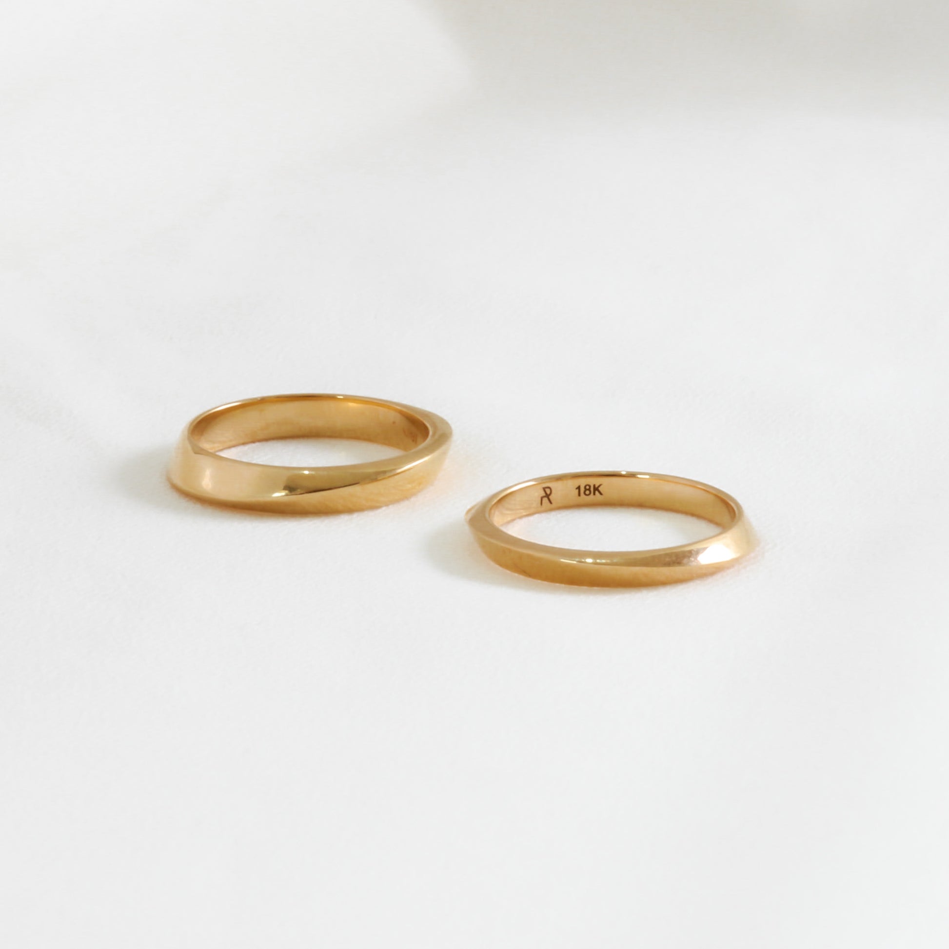 two geometric gold wedding rings on white background