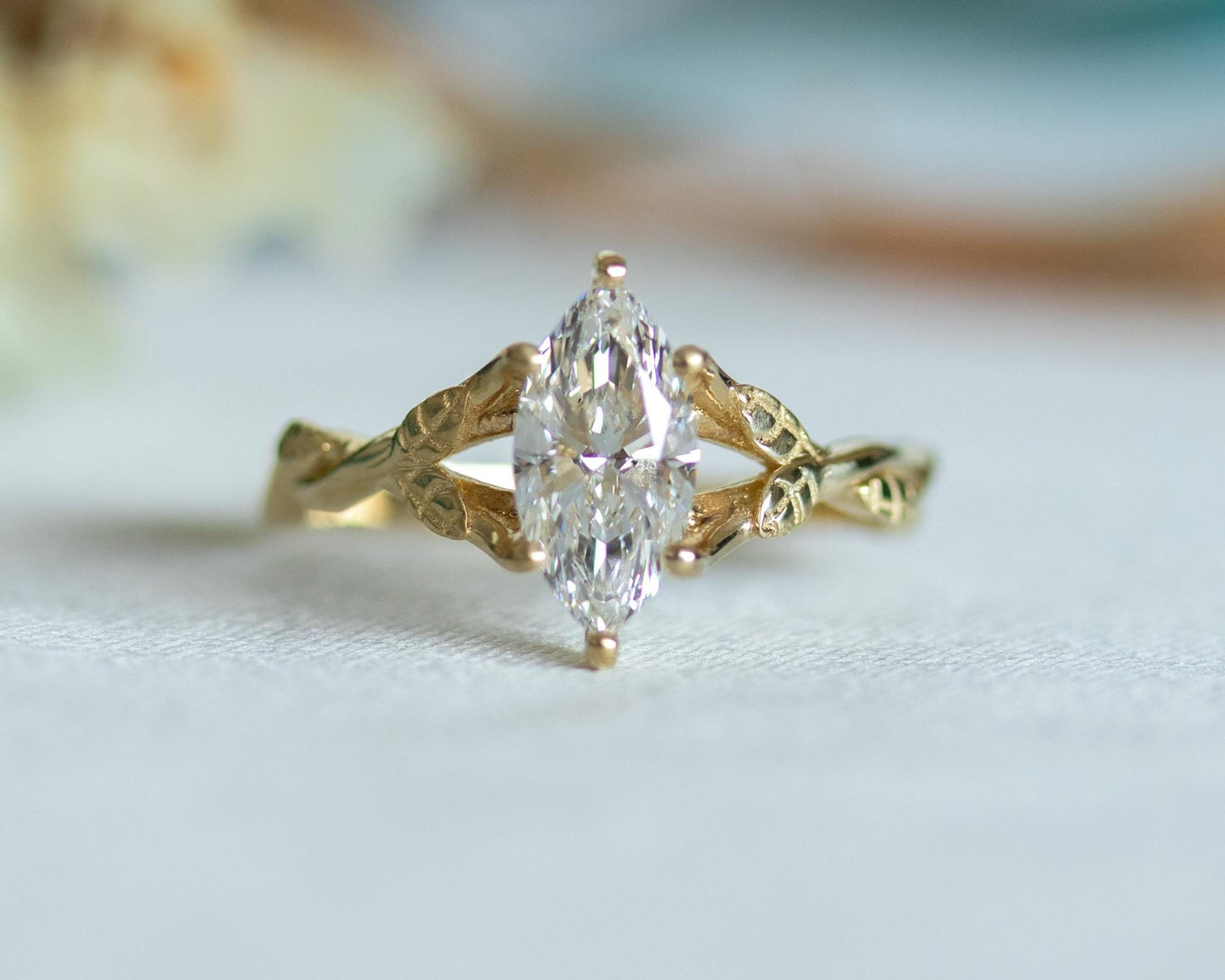 Gold ring with a marquise-shaped diamond on a light background