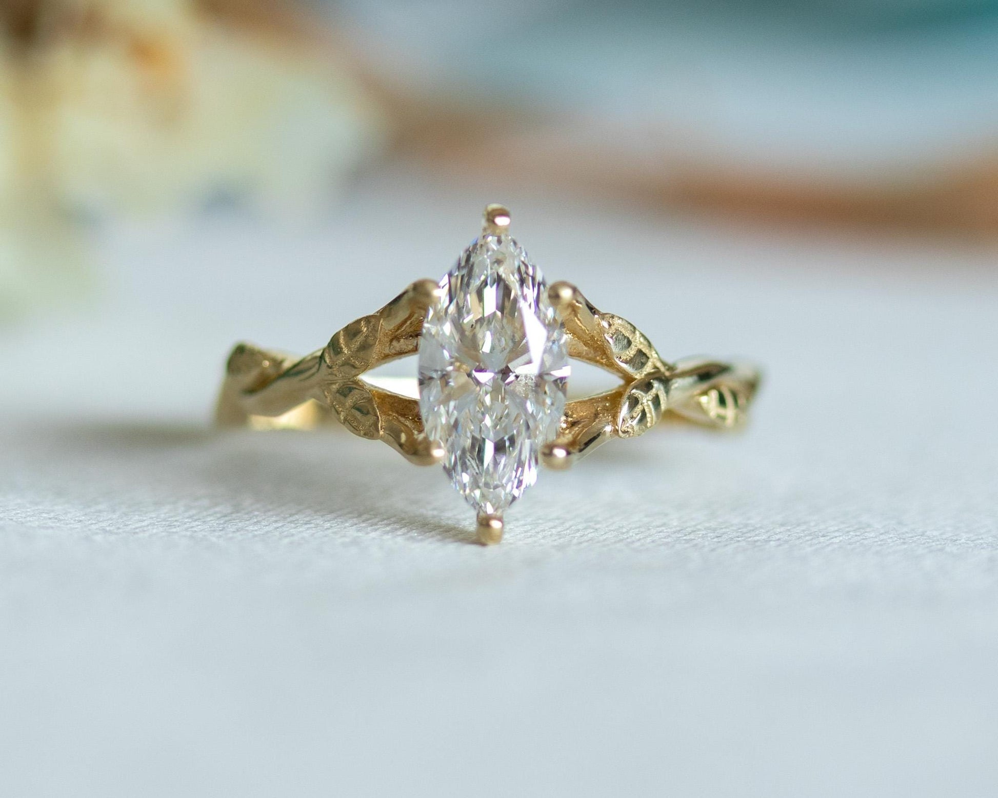 Gold ring with a marquise-shaped diamond on a light background