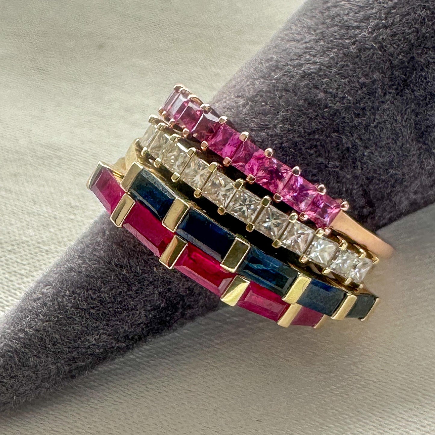 Stack of 14K gold baguette gemstone rings featuring blue sapphires, rubies, pink sapphires, and white diamonds — elegant modern fine jewelry