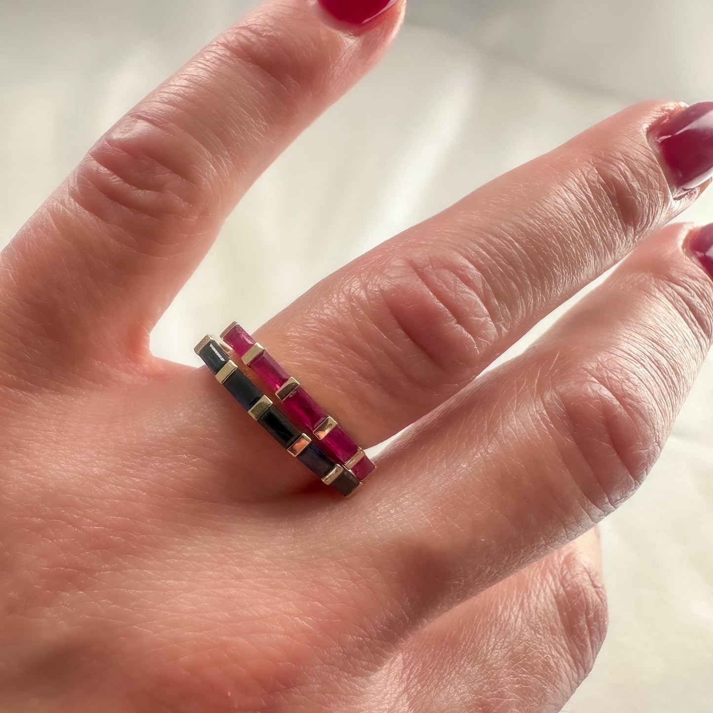 14K gold ruby and blue sapphire baguette rings stacked on hand — elegant modern fine jewelry look