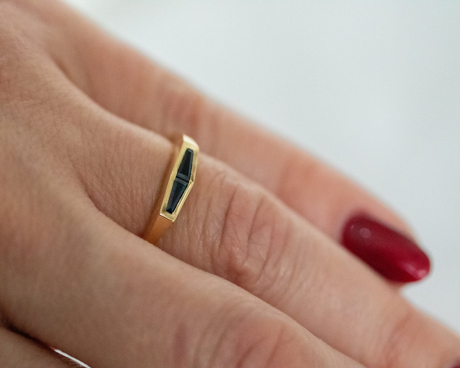 Two natural blue tapered baguette sapphires set in a 14K yellow gold band, worn on the hand.