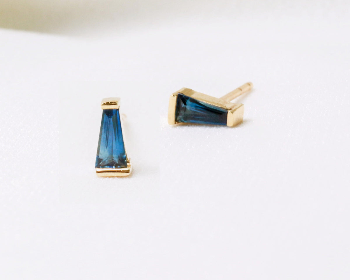Blue tapered baguette sapphire stud earrings bar-set in yellow gold, angled close-up