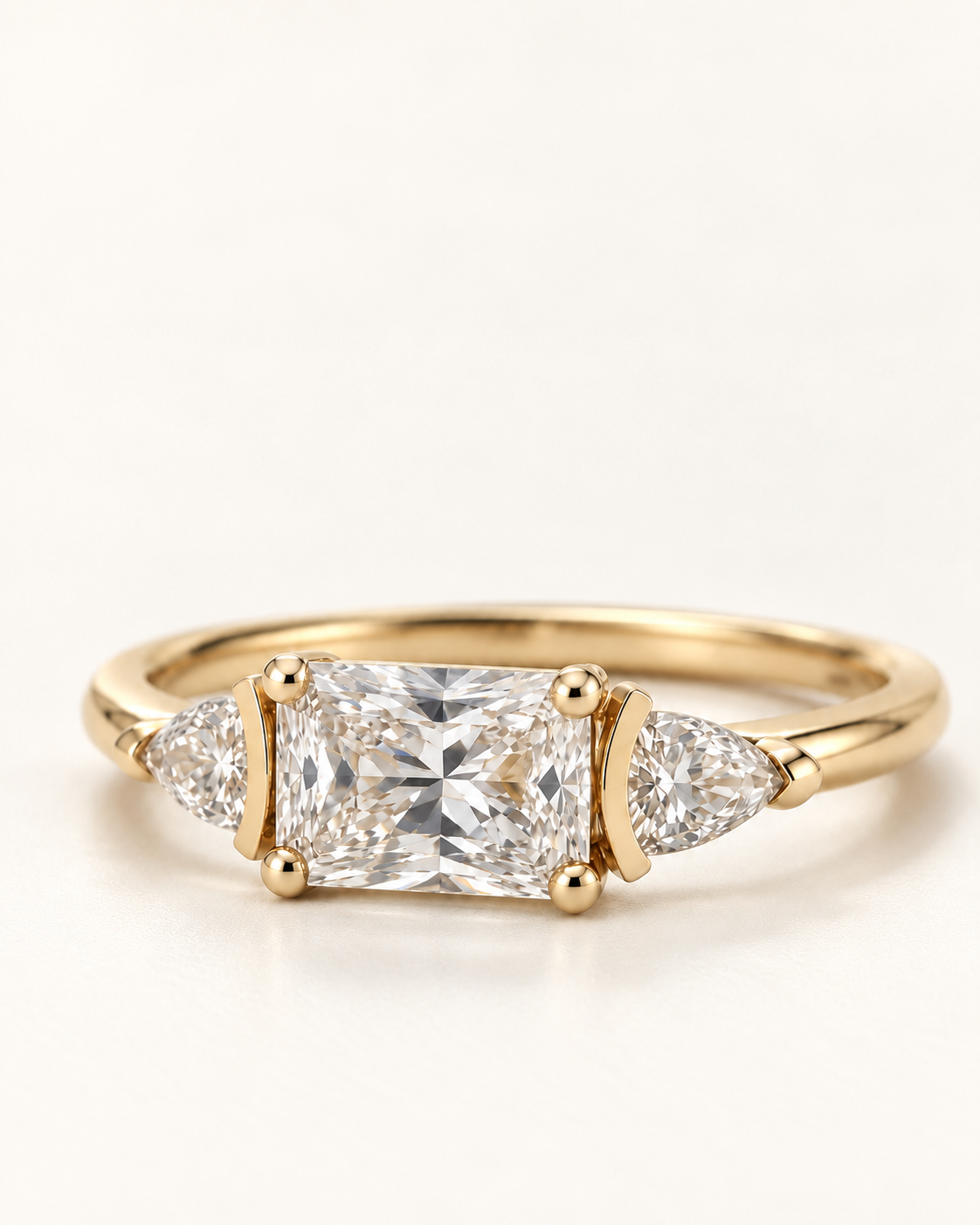 Angled close-up of a radiant-cut diamond ring with trillion side stones in yellow gold