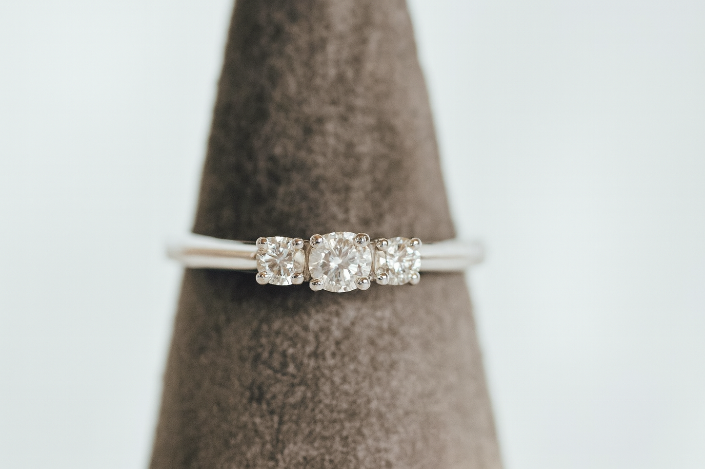 Three stone diamond ring on display cone, white gold setting