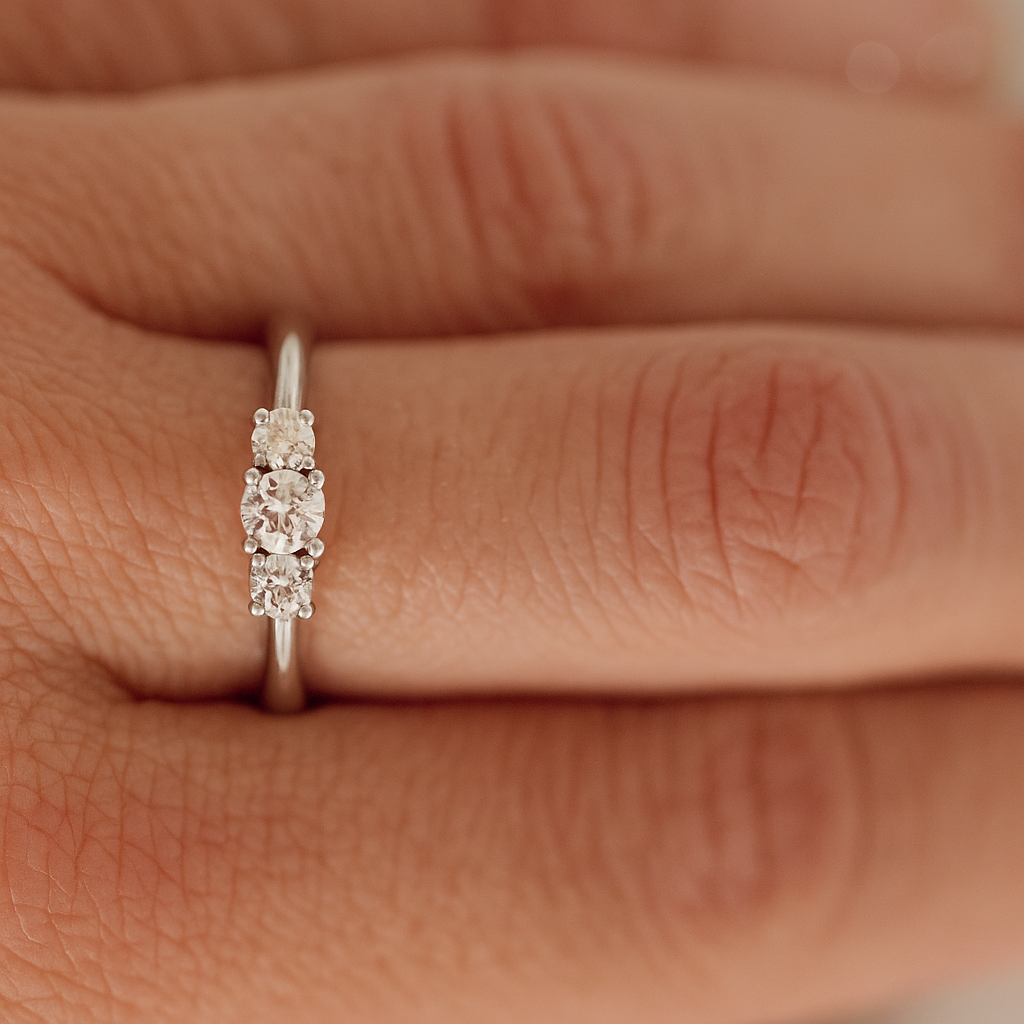 Three stone diamond engagement ring worn on finger, 14K white gold band