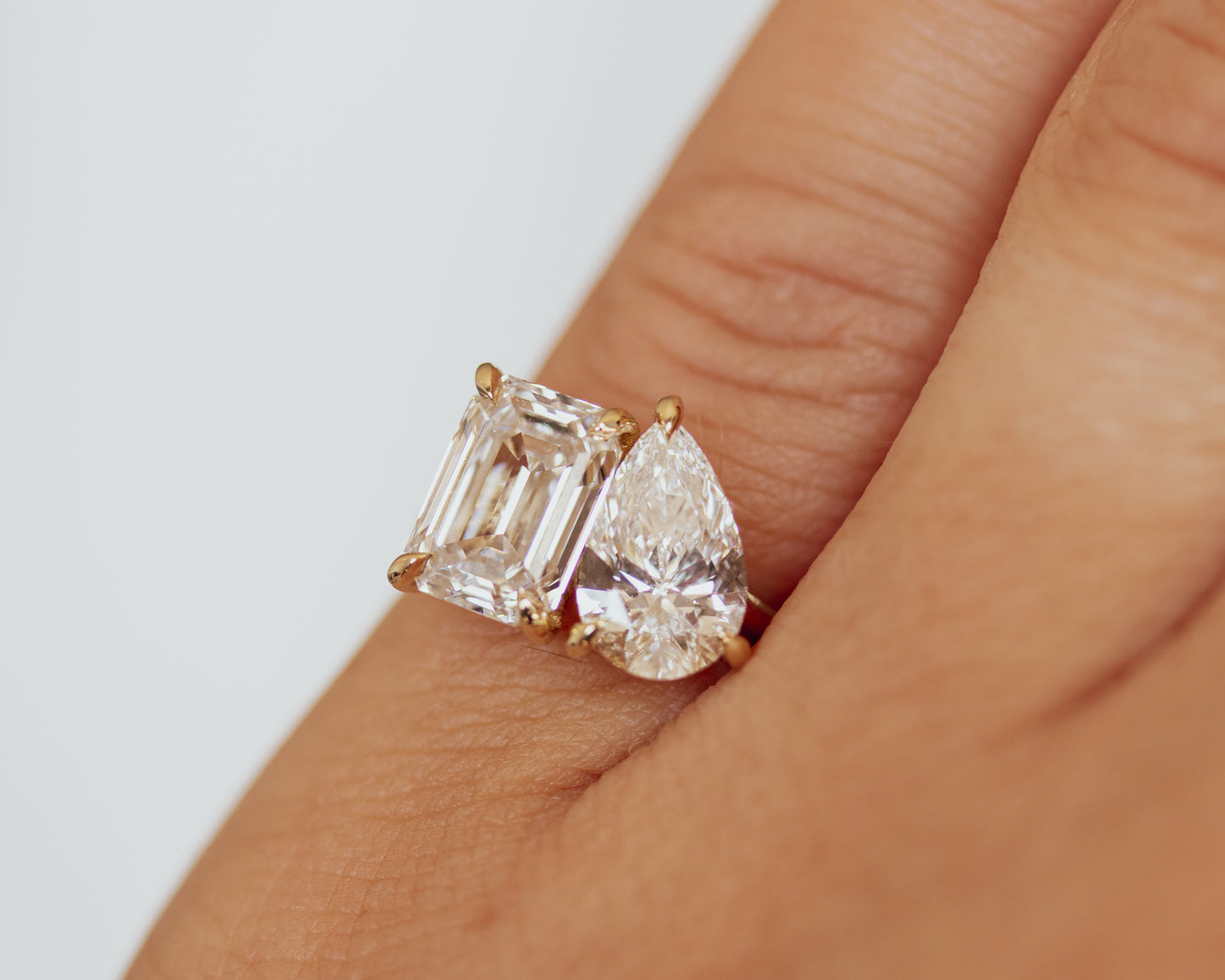 Toi et Moi emerald and pear diamond ring worn on the hand in 14K yellow gold