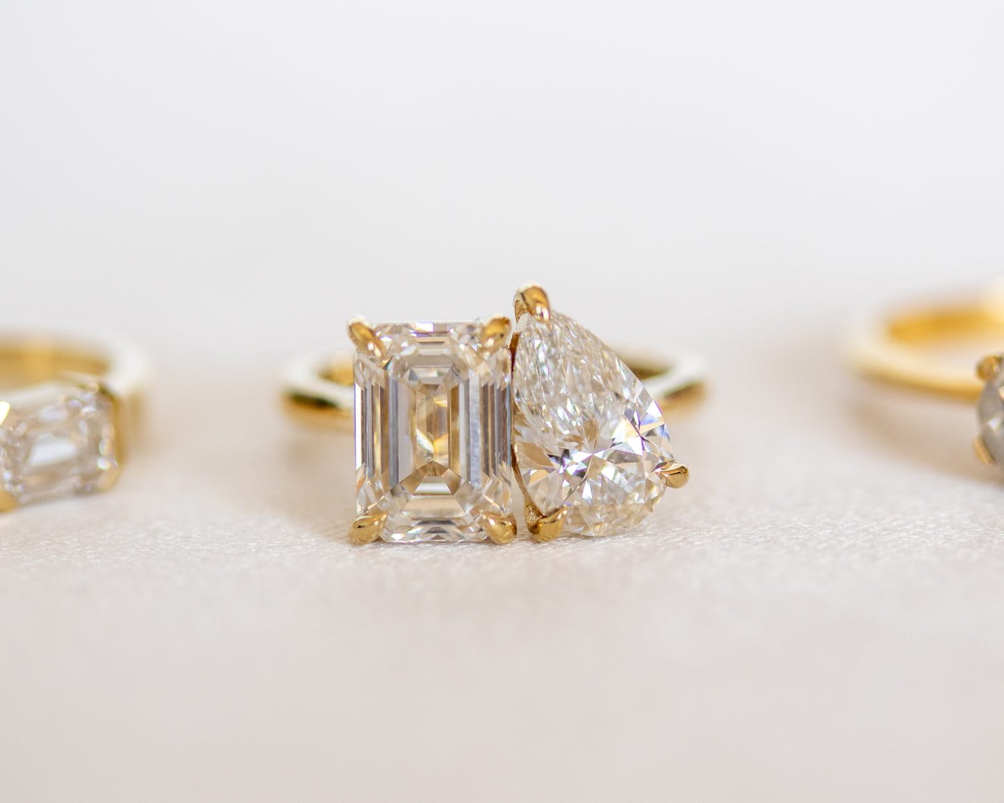 Toi et Moi emerald and pear diamond ring in 14K yellow gold with a soft rose backdrop
