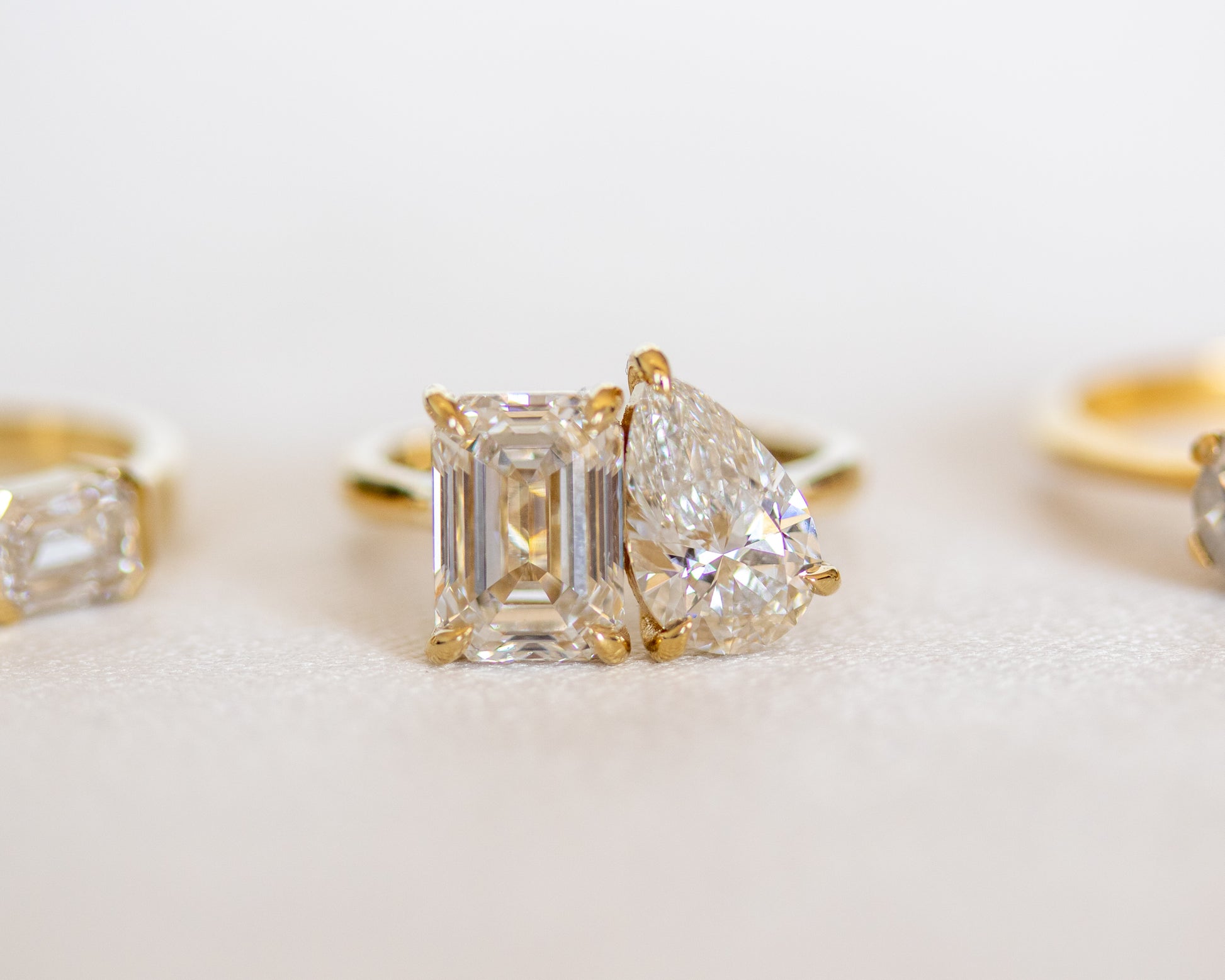 Toi et Moi emerald and pear diamond ring in 14K yellow gold with a soft rose backdrop