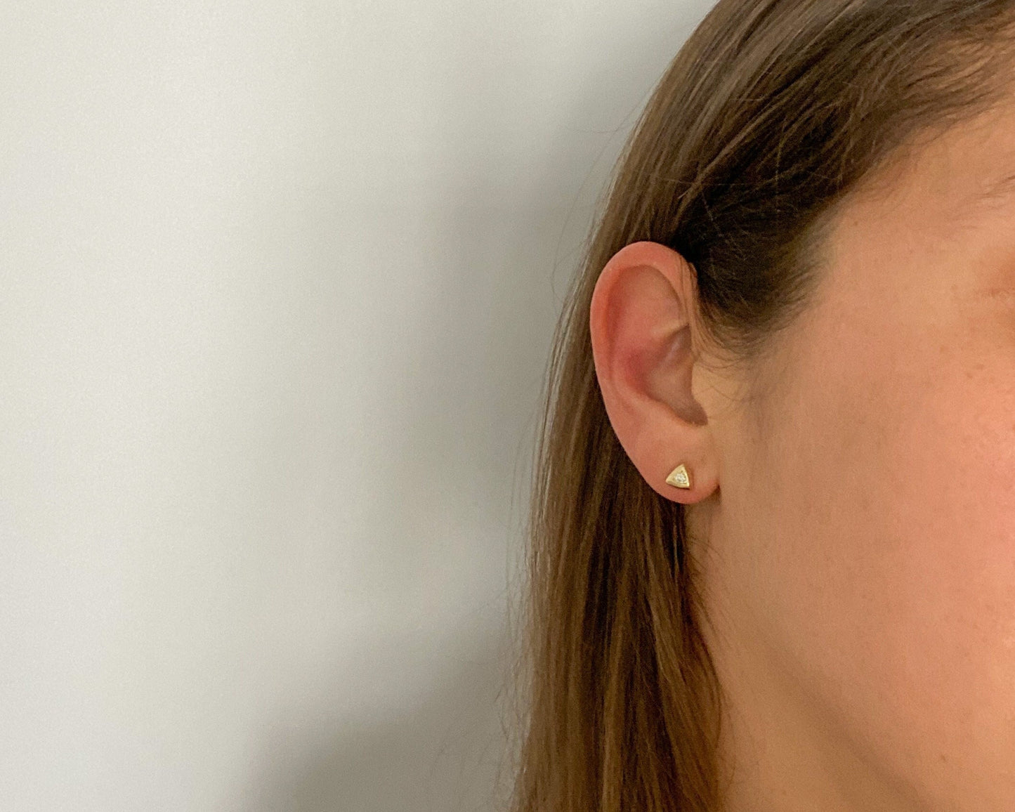 Triangular gold diamond stud earring, side profile on model