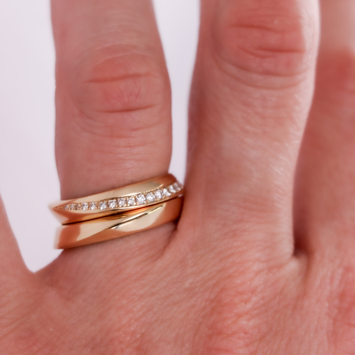 Twisted diamond pavé band and twisted gold band worn on the finger