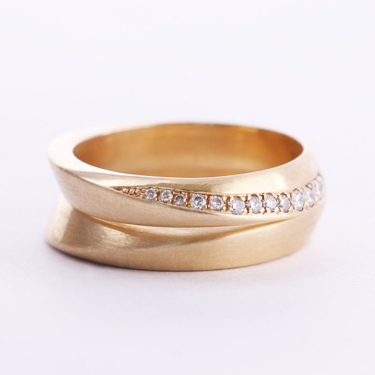 Twisted diamond pavé band stacked on a twisted gold band, white background