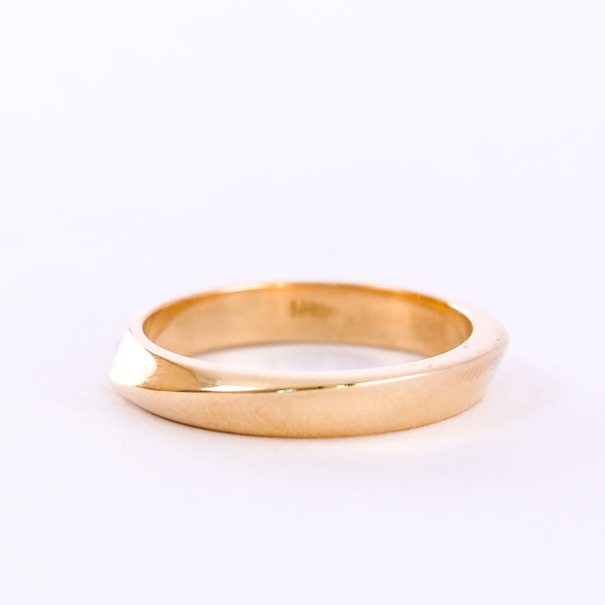 Twisted yellow gold wedding band on a white background, front view