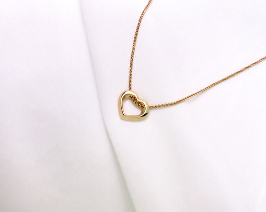 Twisted open heart pendant in 14K yellow gold on a spiga chain, on white fabric