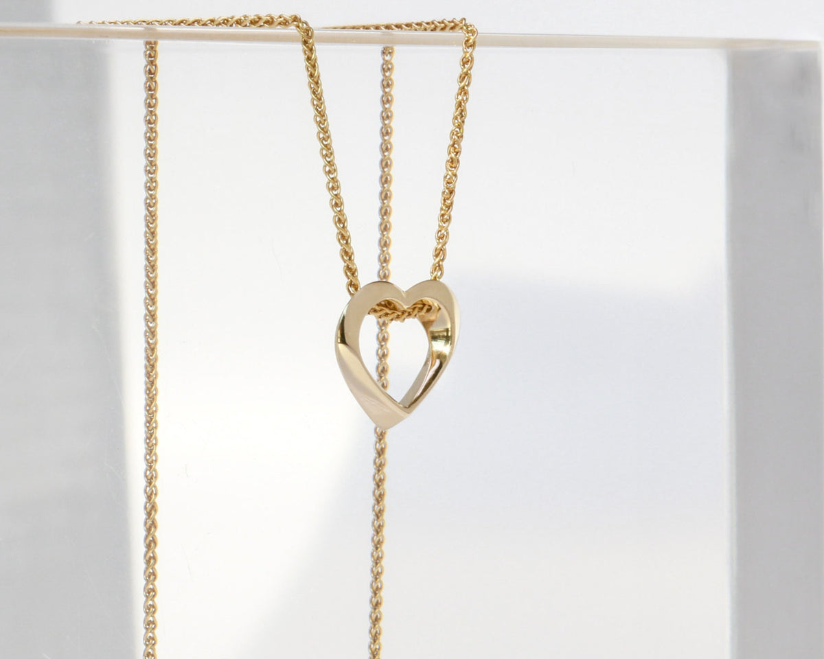 Twisted open heart in 14K yellow gold, angled to show the turn of the gold