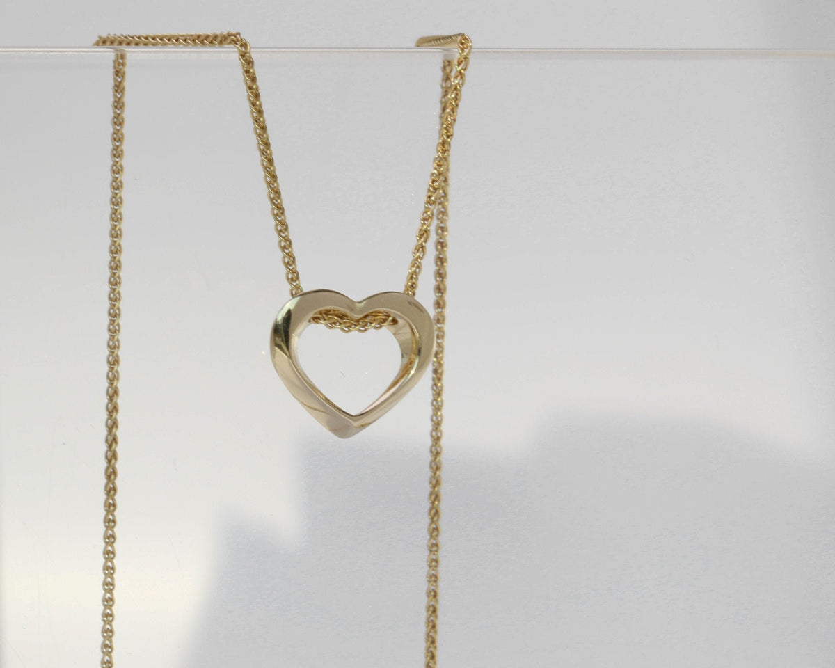 Twisted open heart pendant in 14K yellow gold hanging on a spiga chain, front view