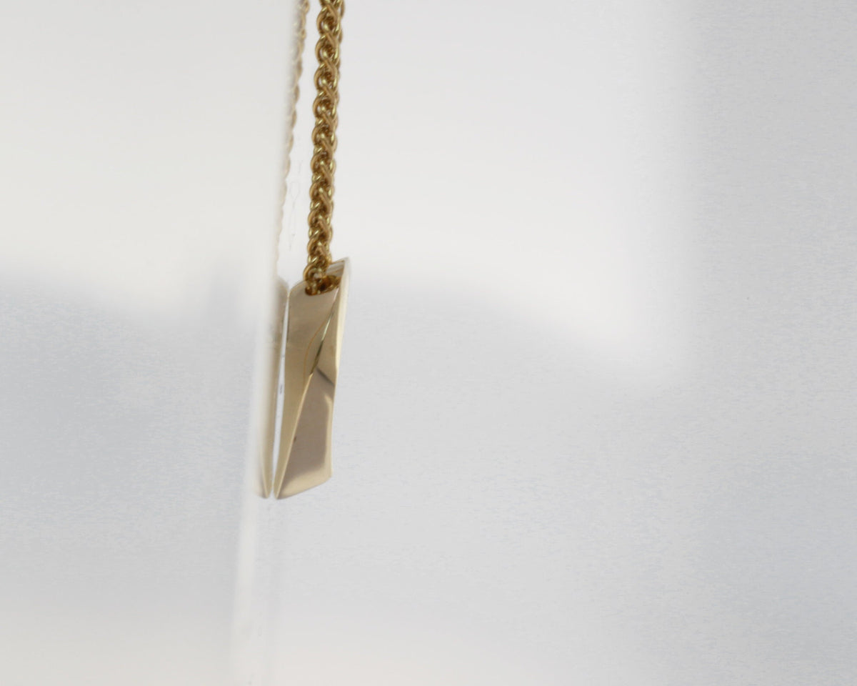 Side profile of a 14K yellow gold twisted open heart pendant on a spiga chain