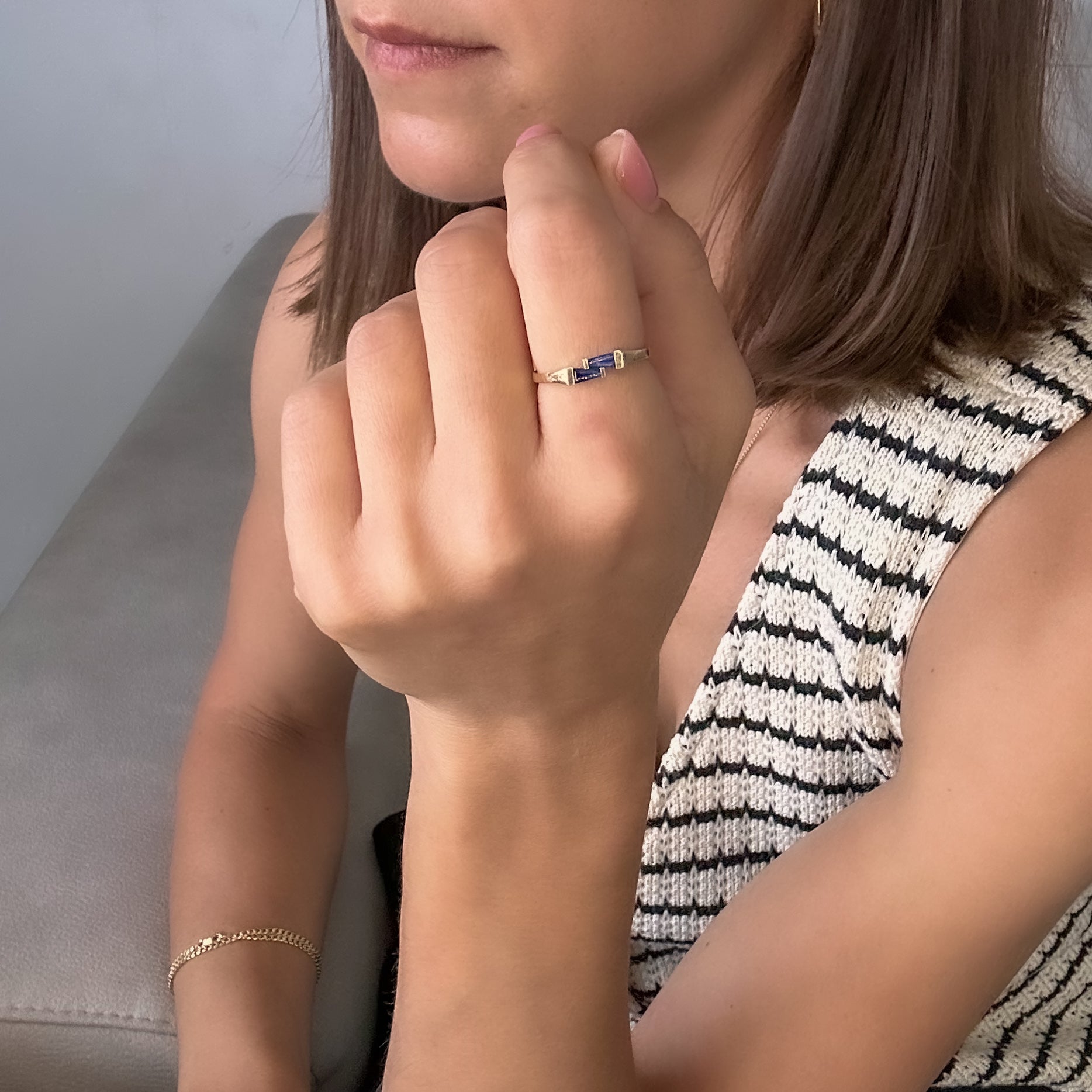A gold ring with two blue sapphires set cheek to cheek on women's finger.