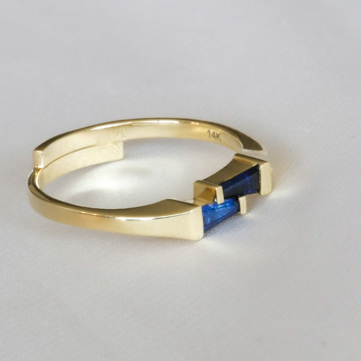14K yellow gold offset two-stone ring with tapered baguette blue sapphires, angled view