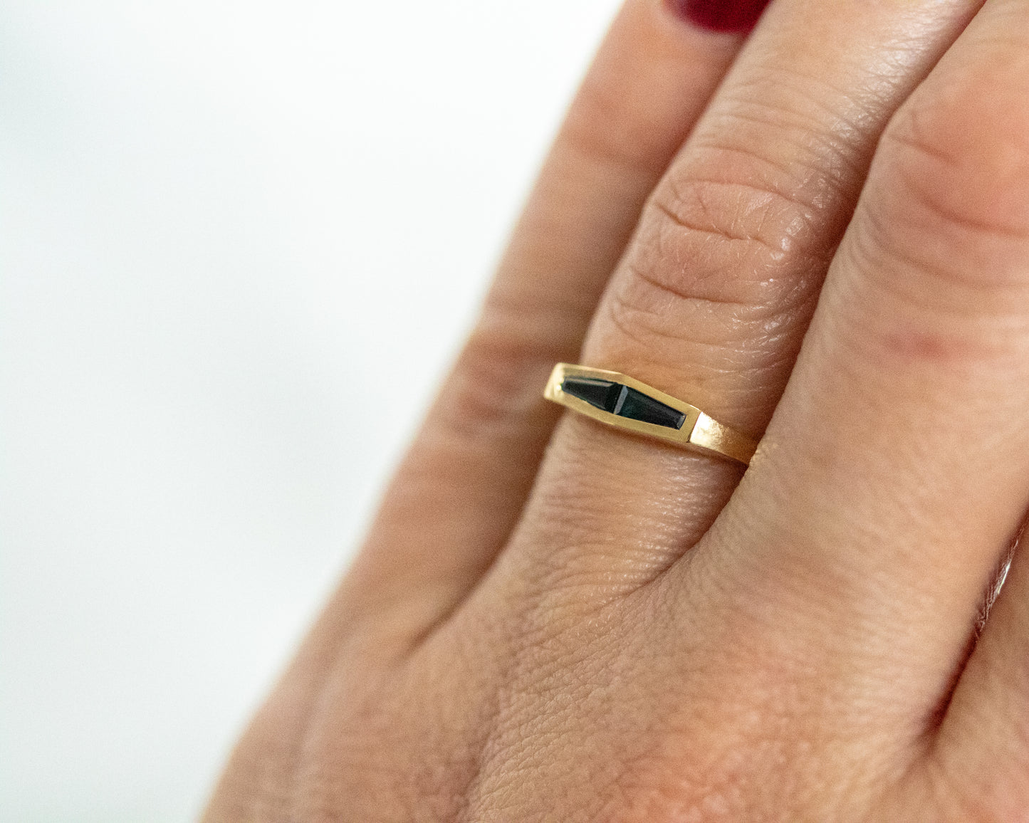 Two-stone tapered baguette blue sapphire ring in 14K yellow gold, close-up on the finger.