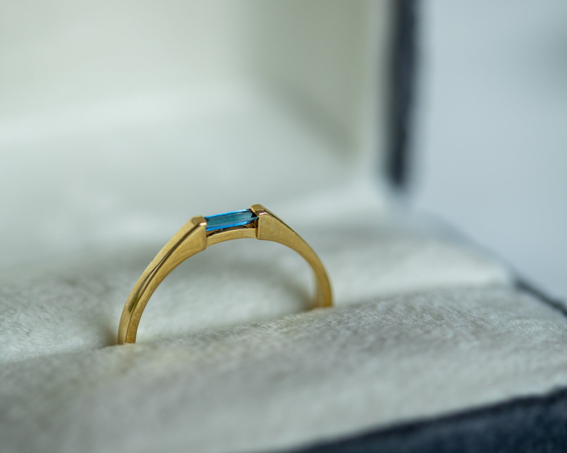 Gold ring with a blue gemstone on a textured surface