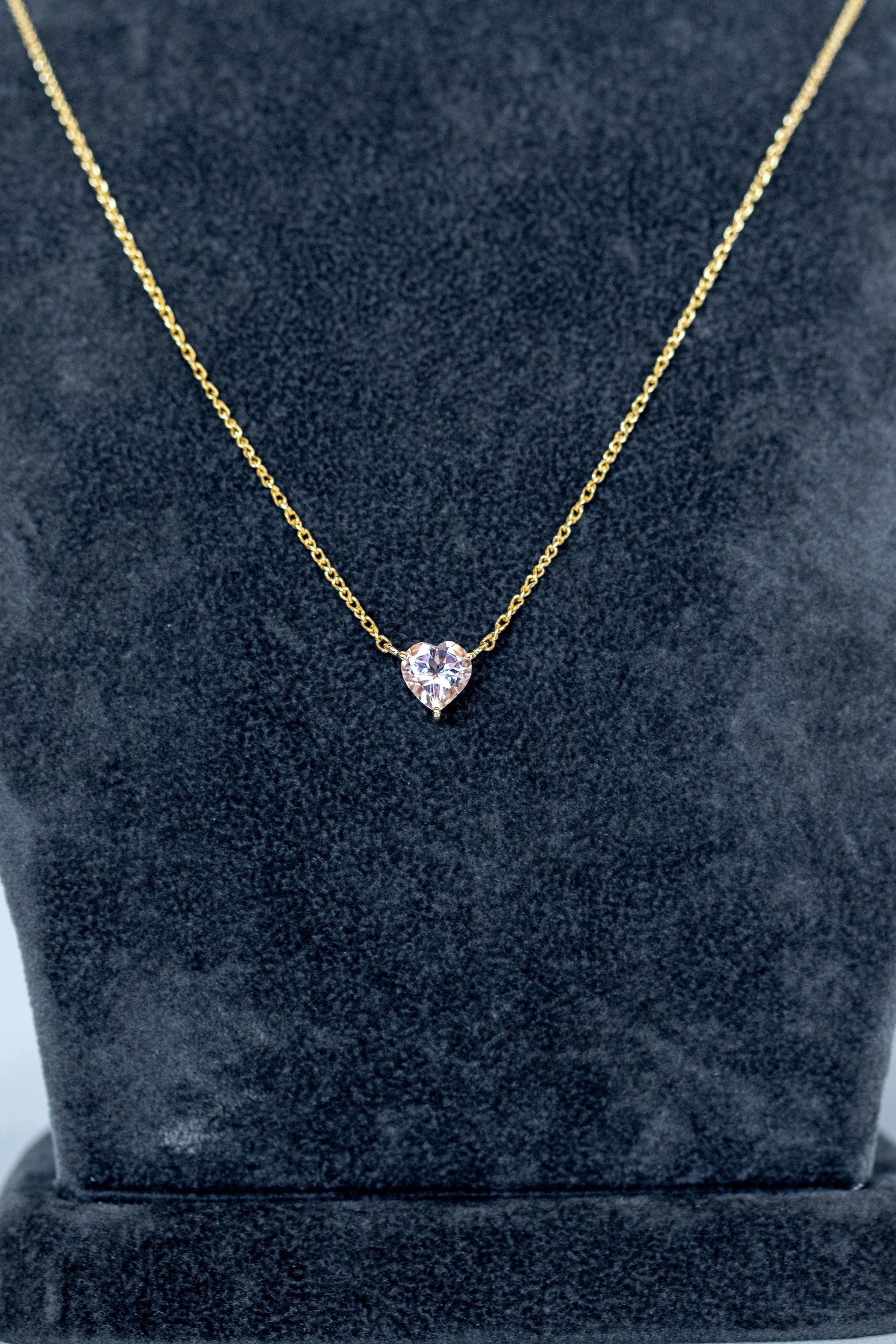 Heart-cut morganite solitaire necklace in 14K gold on gray-blue background