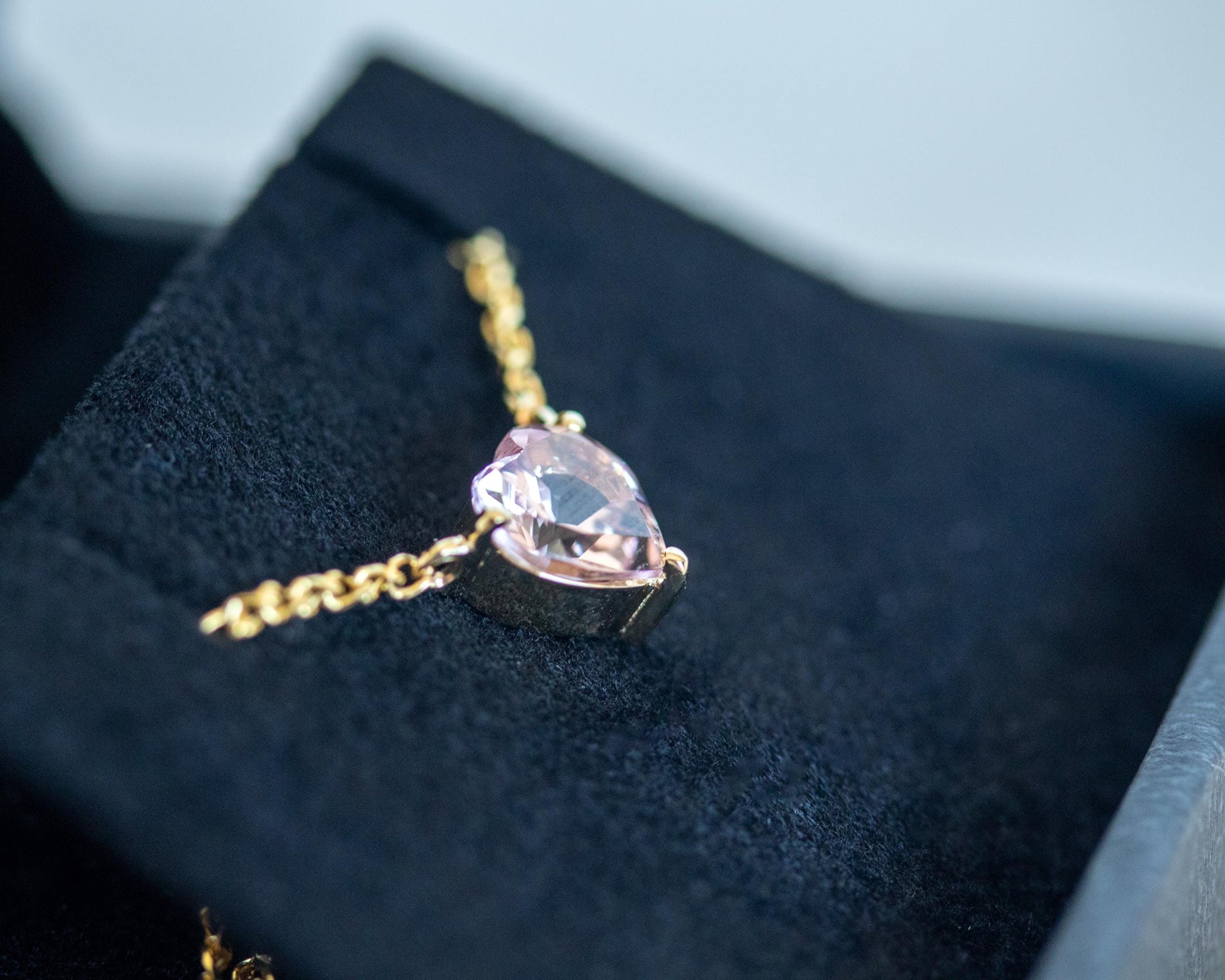 Heart-shaped pink gemstone necklace on a dark surface