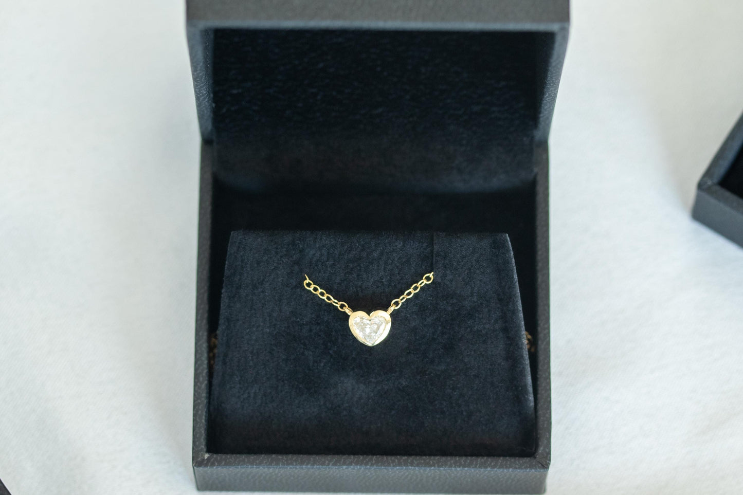 Gold necklace with a heart pendant in a black jewelry box on a white background