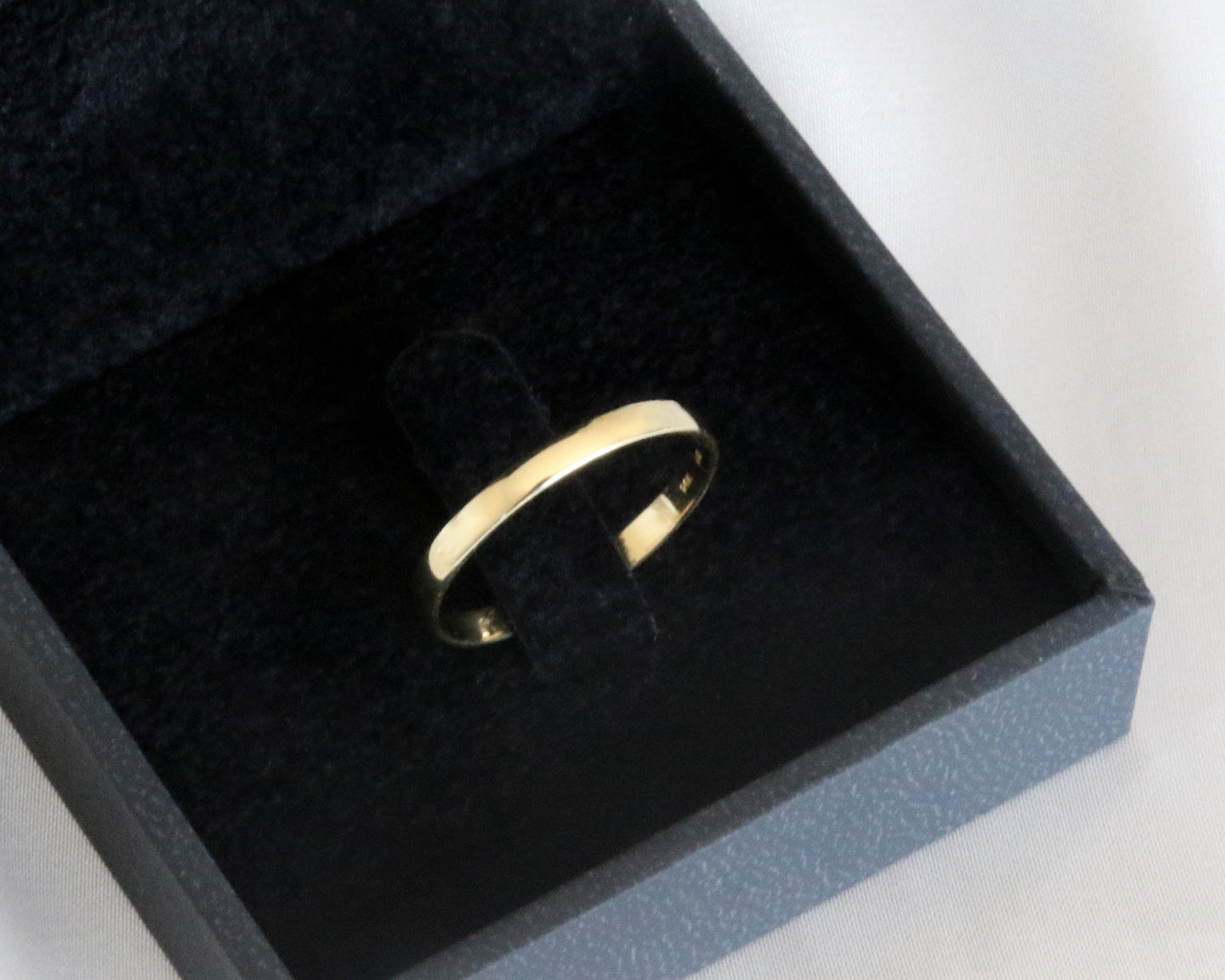 Gold ring in a black jewelry box on a white background