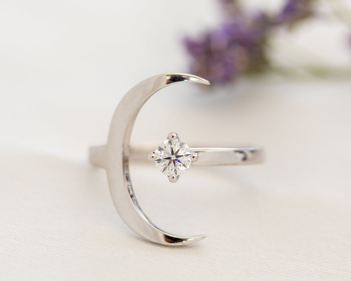 White gold crescent moon ring with a prong-set round diamond, front view