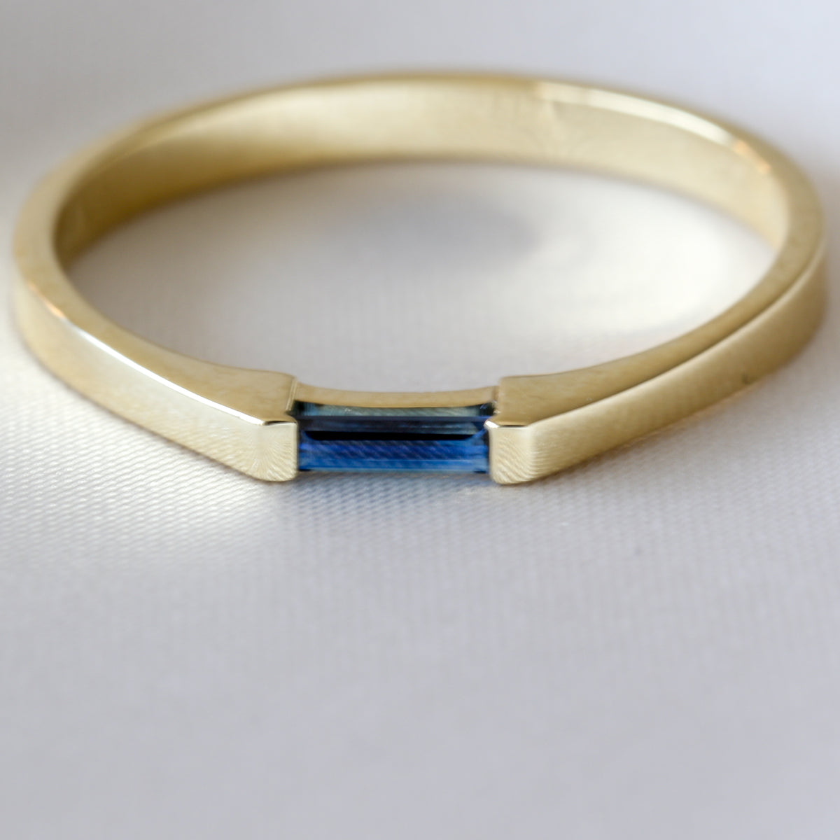 14K yellow gold ring with a needle baguette blue sapphire set east-west, on white