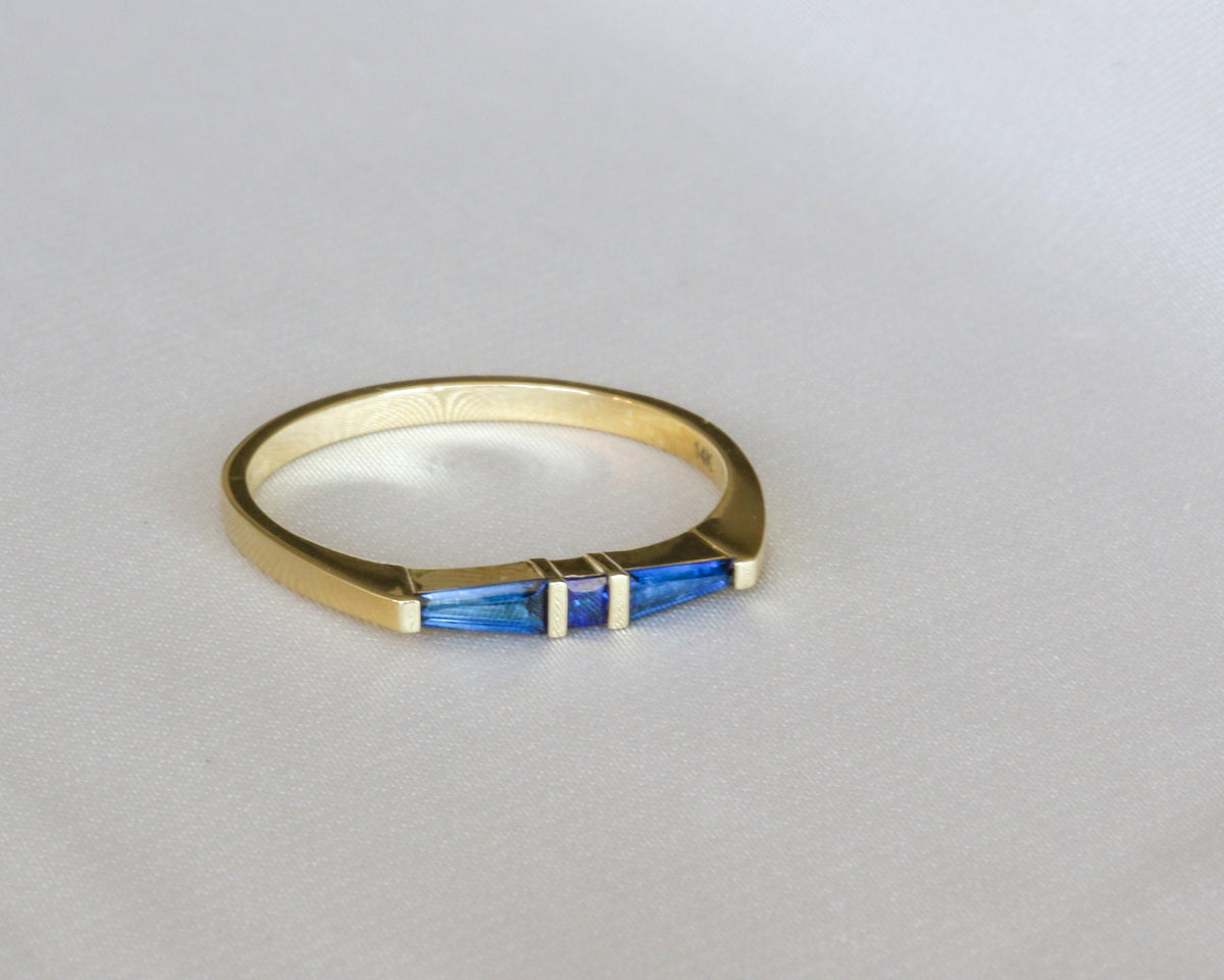 Angled view of a yellow gold three-stone sapphire ring showing the inside of the band