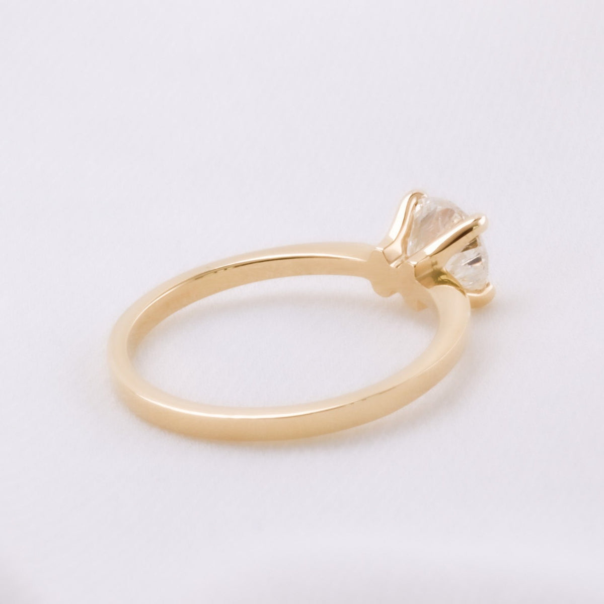 Back view of a yellow gold solitaire ring showing the four-prong setting