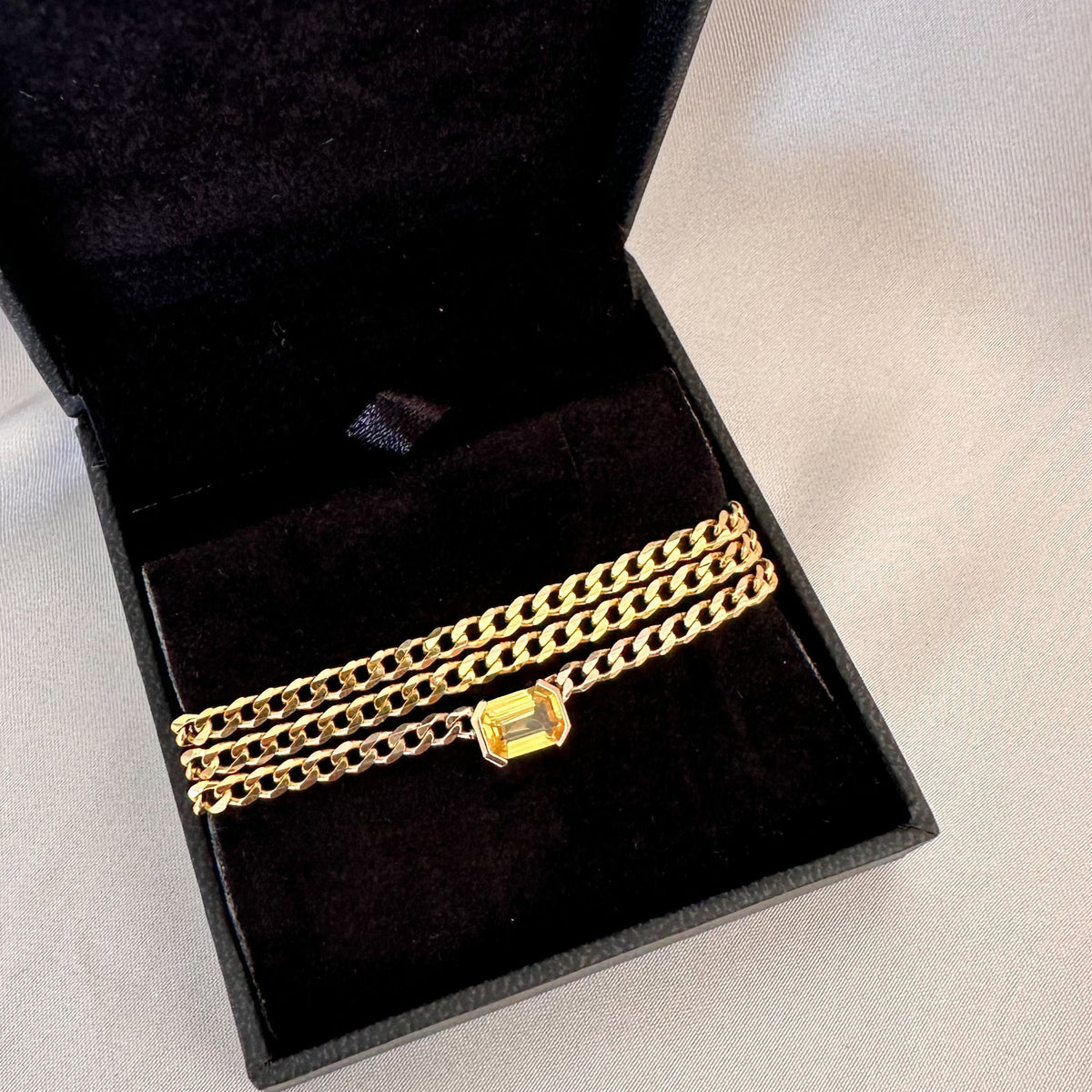Fine 14K gold curb chain choker with an emerald cut yellow sapphire in a black jewelry box